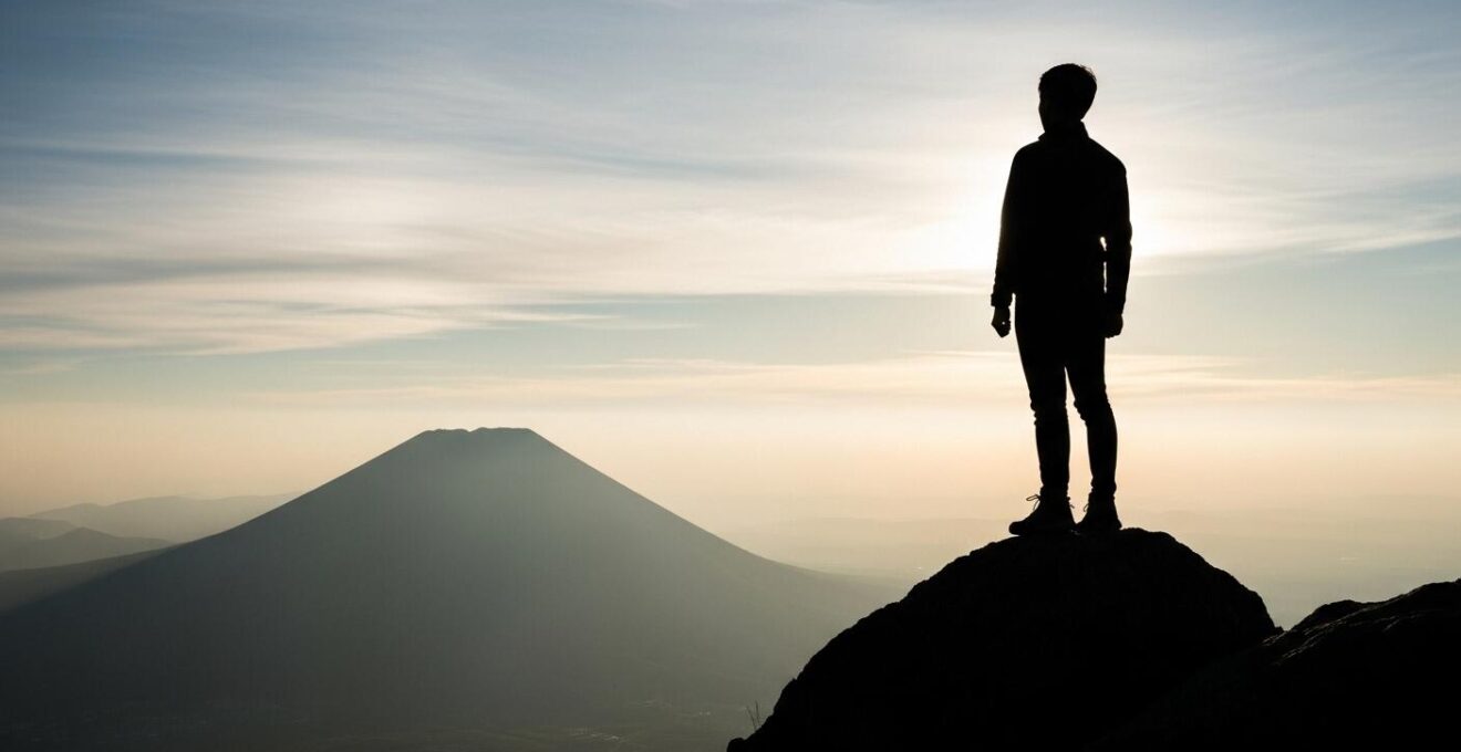 Une personne debout au sommet d'une montagne au lever du soleil, regardant vers l'horizon vaste symbolisant la liberté et l'indépendance entrepreneuriale